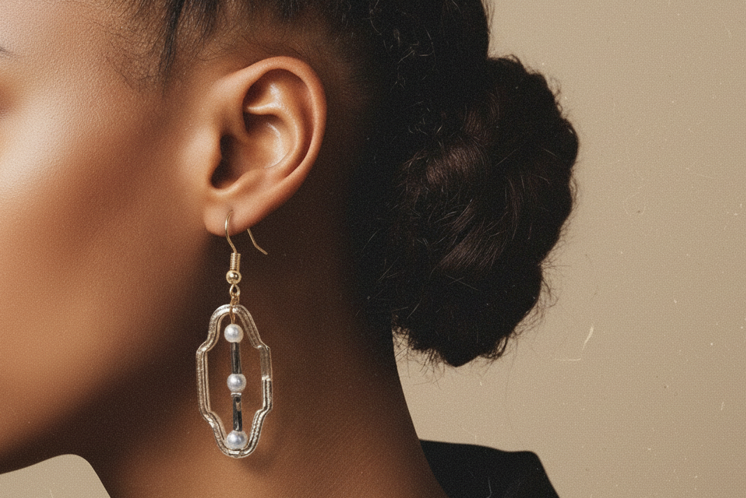 Close-up of an ear wearing a gold earring with pearls.